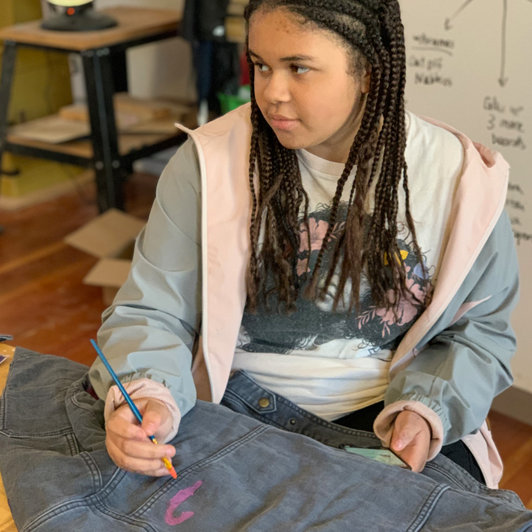 Girls Garage teen artist painting on jacket provided by Dovetail Workwear