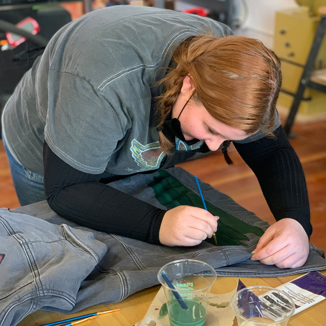Student painting kelp onto jacket